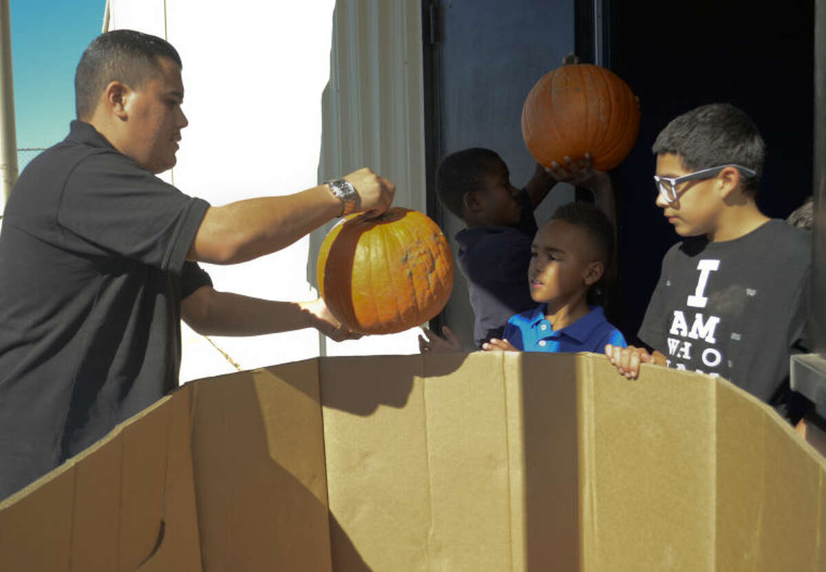 Michael Jasso, former Boys and Girls Club participant, is now Boys and Girls Club unit director in Midland gets help unloading a crate of pumpkins at the center. Tim Fischer\Reporter-Telegram