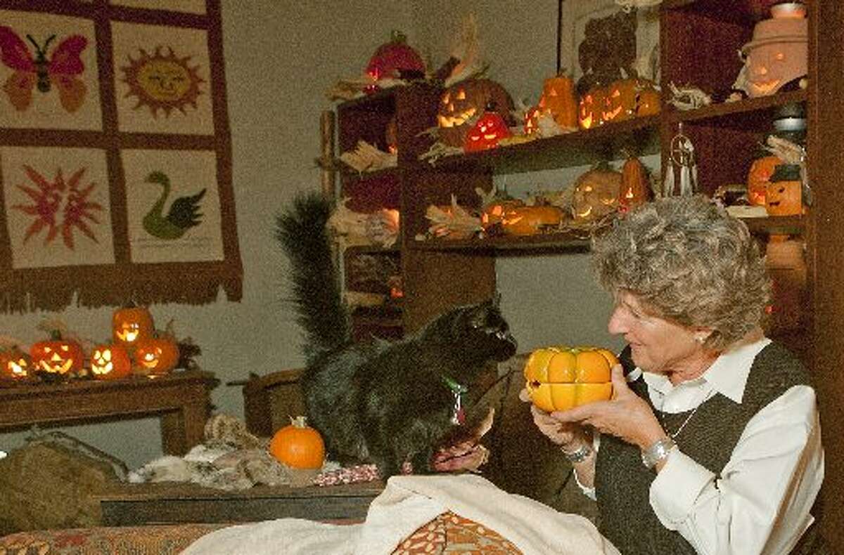 Brenda Rathjen and her 2-year-old rescue cat Loonie check out one of the 150 jack-o-lanterns in Rathjen's house on Wednesday.