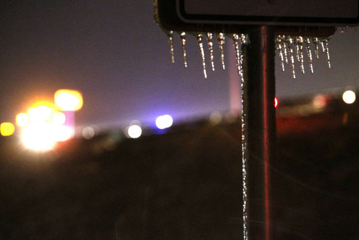Icecicles hang from a sign as Midland public safety personnel work a vehicle accident in the background near the 191 and FM 1788 overpass Saturday. James Durbin/Reporter-Telegram