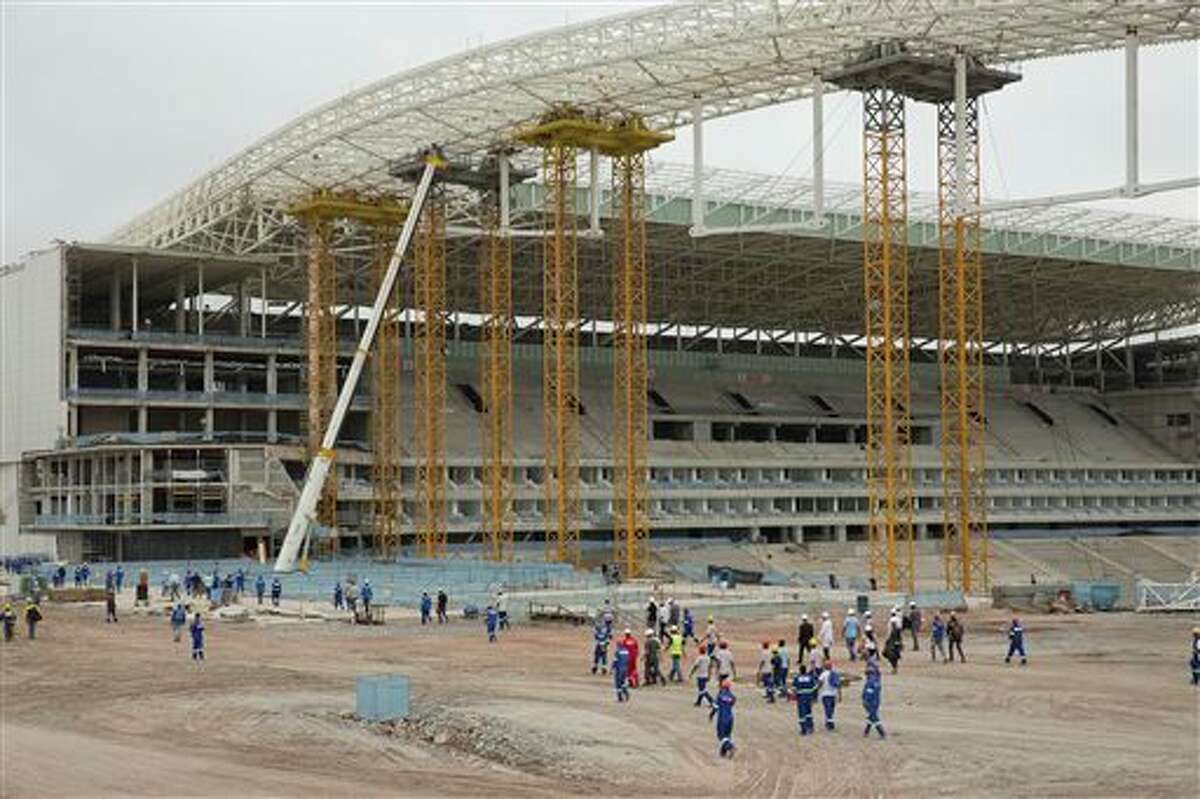 Construction workers return to the Arena Corinthians stadium that will host the opening match of the World Cup, five days after an accident killed two workers, in Sao Paulo, Brazil, Monday, Dec. 2, 2013. Construction company Odebrecht had suspended work on the site after a crane collapsed on Wednesday, Nov. 27, as it was hoisting a 500-ton piece of roofing. (AP Photo/Andre Penner)