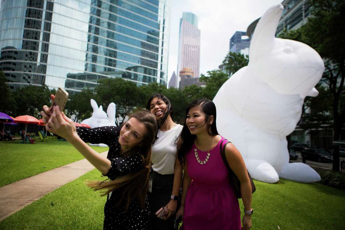 (left to right) Virjinia Hadjieva, Erika Arredondo, and Wynne Chan gather for a selfie by Australian artist Amanda Parer's monumental installation "Intrude" in downtown Houston, Tuesday, May 10, 2016, in Houston. The ladies walked a block to take a closer look at the bunnies and for photos. ( Marie D. De Jesus / Houston Chronicle )