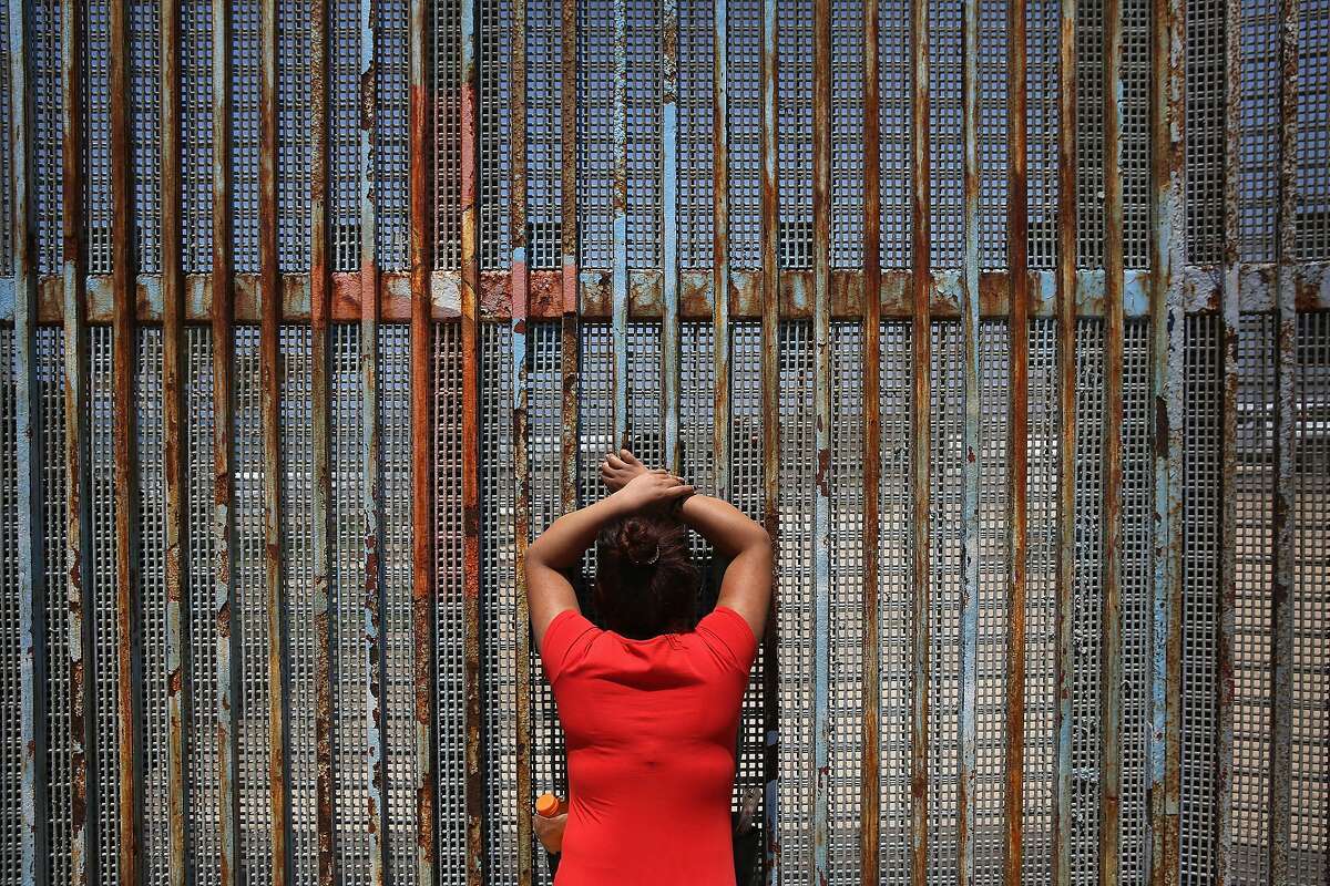 TIJUANA, MEXICO - MAY 01: Gabriella Ramirez, 23, speaks to her boyfriend, a construction worker who immigrated to California, through the U.S.-Mexico border fence on May 1, 2016 in Tijuana, Mexico. Mexicans on the Tijuana side can approach the border fence at any time. The U.S. Border Patrol, however, tightly controls the San Diego, CA side and allows visitors to speak to loved ones through the fence during restricted weekend hours at "Friendship Park". The park is the only place along the 1,954-mile border where such interactions are permitted by U.S. authorities. On only three occassions have U.S. officials allowed a gate to be opened at the park for pre-screened separated family members to embrace. (Photo by John Moore/Getty Images)