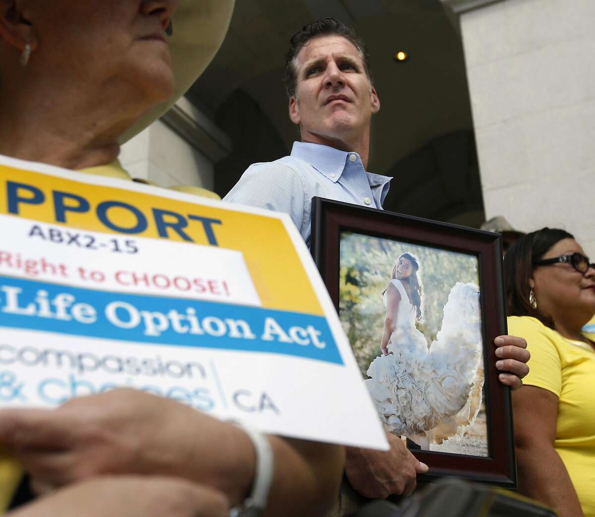 Dan Diaz holds a photo of his late wife, Brittany Maynard during a rally calling for California Gov. Jerry Brown to sign the right to die legislation at the Capitol in Sacramento, Calif., Thursday, Sept. 24, 2015. Maynard was the 29-year-old California woman with brain cancer who moved to Oregon to legally end her life. The measure, approved by both houses of the Legislature, faces an uncertain future with Brown, a former Jesuit seminarian who has not said whether he will sign it. (AP Photo/Rich Pedroncelli)