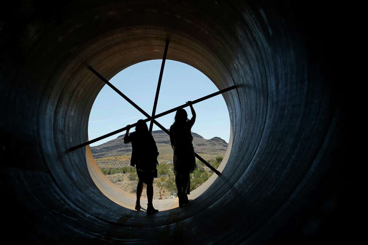 People stand in a metal tube after a test of a Hyperloop One propulsion system, Wednesday, May 11, 2016, in North Las Vegas, Nev. The startup company opened its test site outside of Las Vegas for the first public demonstration of technology for a super-speed, tube based transportation system. (AP Photo/John Locher)
