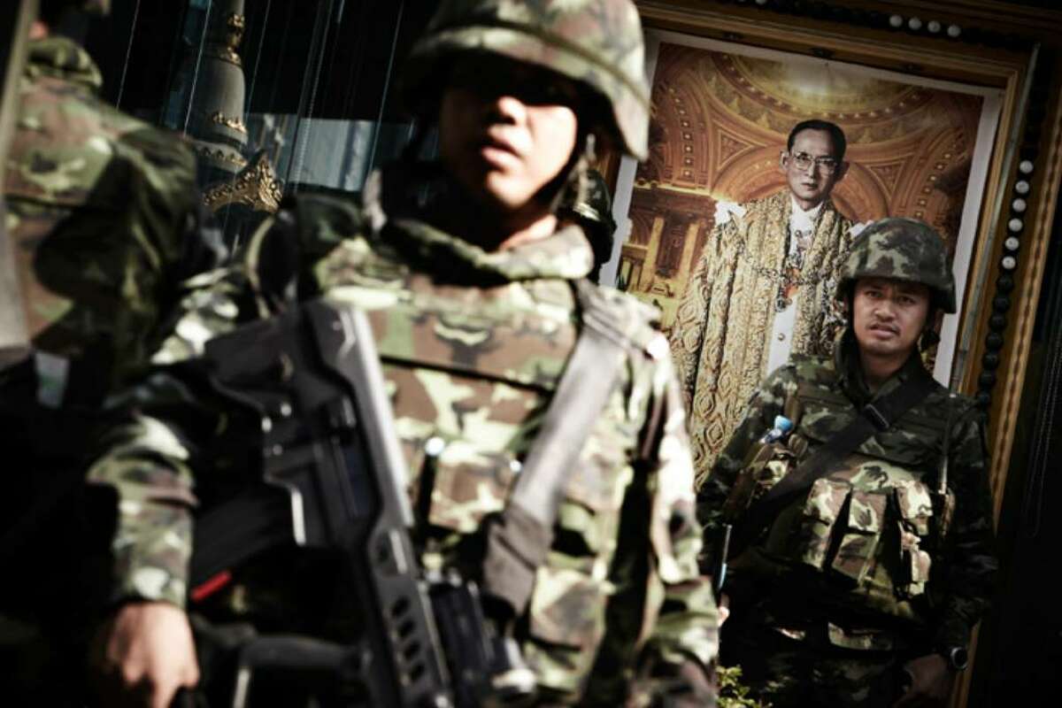 BANGKOK, THAILAND - APRIL 19: Thai army soldiers stand alert next to the picture of Thai King Bhumibol Adulyadej at Bangkok's Silom district as Red shirt supporters of ousted premier Thaksin Shinawatra threaten to take their protest to the financial district of Bangkok on April 19, 2010 in Bangkok, Thailand. The army have vowed not to let the protestors move, whilst the anti-Thaksin yellow shirt PAD protestors gave the government a week to end the crisis or claimed they would take matters into their own hands. (Photo by Athit Perawongmetha/Getty Images)