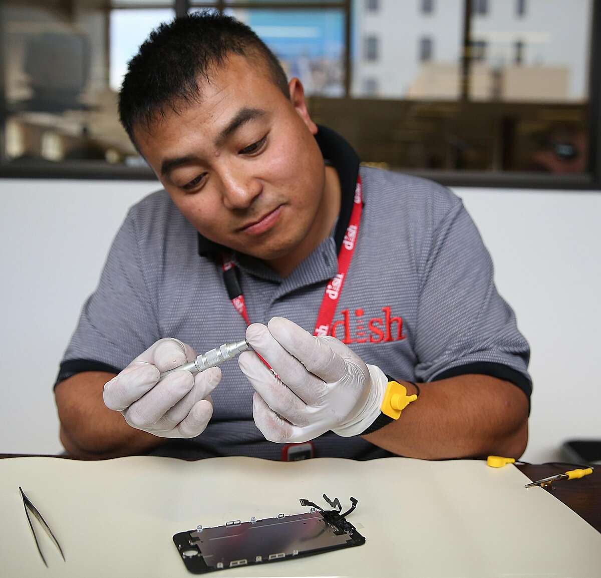 Dish employee Johnson Chuong takes apart an iPhone to fix a cracked screen on site in the Chronicle building.