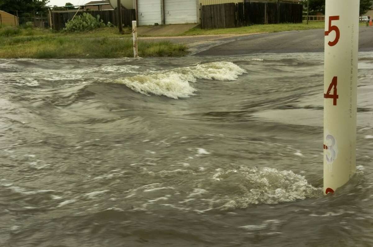 Flood waters still form waves as they rush down the draw Wednesday moring crossing Benton Street. Photo by Tim Fischer/Midland Reporter-Telegram