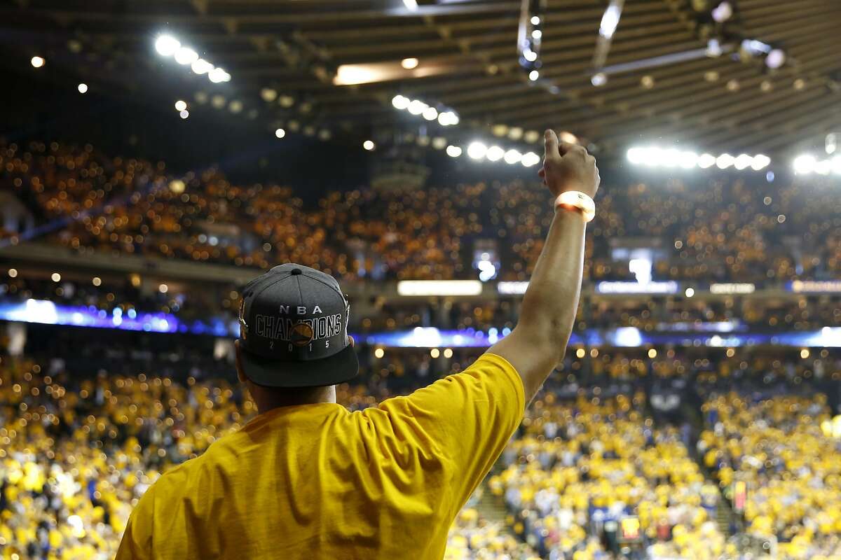 A fan raises his arm in celebration during the first game of the Western Conference Finals between the Warriors and the Oklahoma City Thunder at Oracle Arena in Oakland, California, on Monday, May 16, 2016.