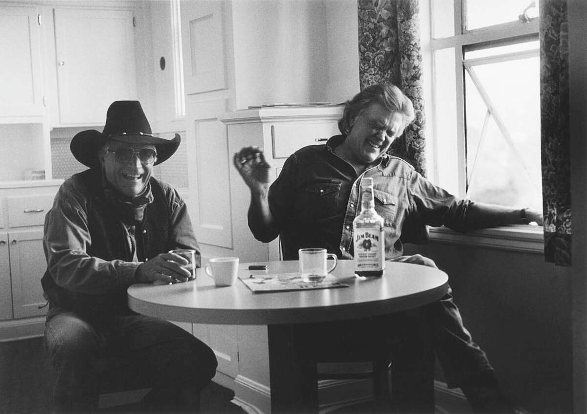American musicians Ramblin' Jack Elliott (left) and Guy Clarke shate a laugh as they sit at a table, San Francisco, California, 2000. (Photo by Chris Felver/Getty Images)