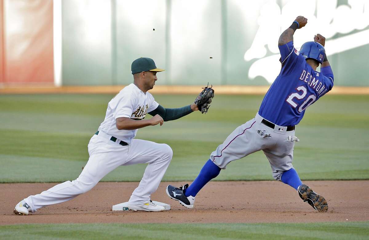 Marcus Semien (10) tries to apply the tag to Ian Desmond (20) on a ball hit to first by Nomar Mazara in the first inning as the Oakland Athletics played the Texas Rangers at the Oakland Coliseum in Oakland, Calif., on Tuesday, May 17, 2016. Desmond was ruled safe on the play.