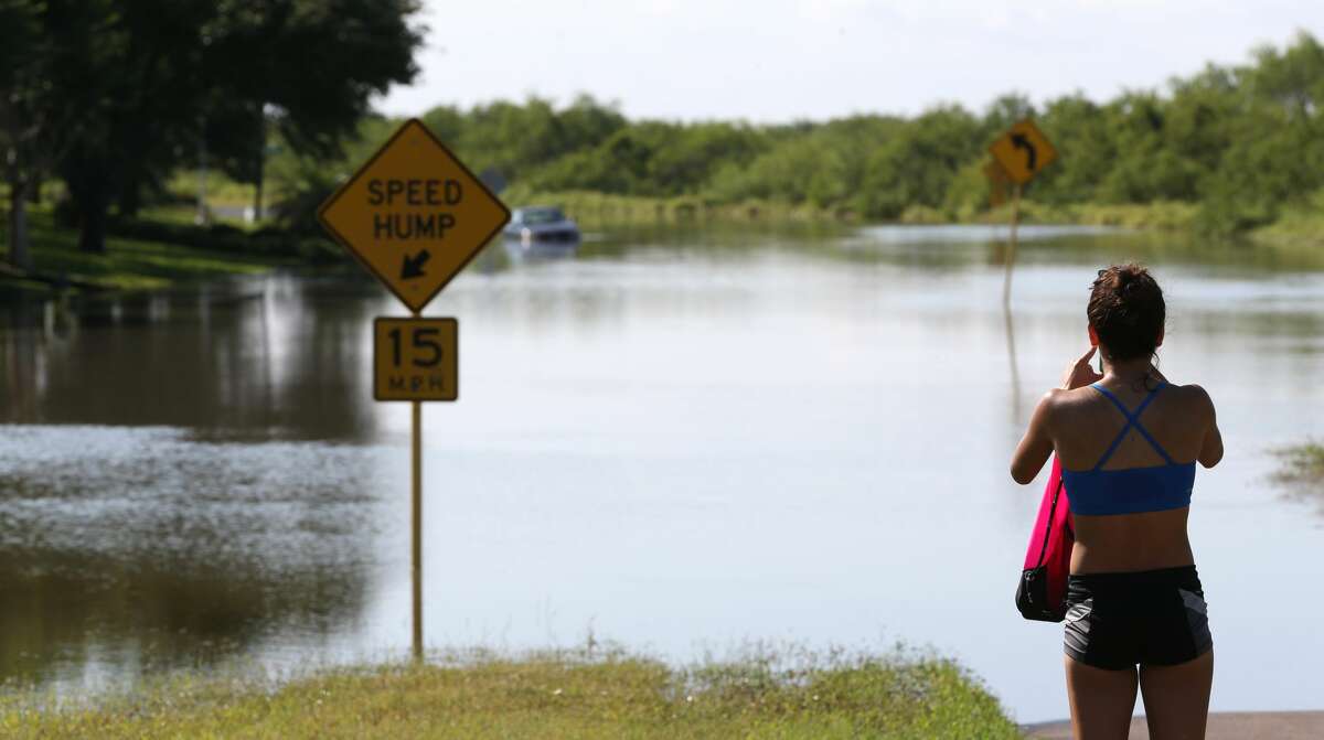 Regina Salinas takes pictures of flooding on Oso Parkway on Monday, May 16, in Corpus Christi. Thunderstorms in South Texas that dumped up to a foot of rain have led to flood-related rescues in Corpus Christi and sewage spilled into a creek.