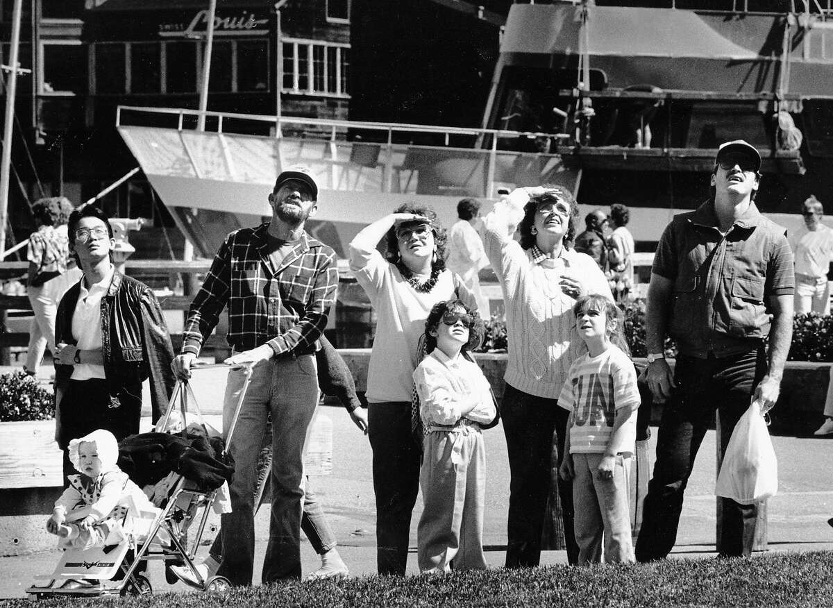 Tourists look skyward to watch a kite-flying contest near Pier 39 on March 29, 1987.