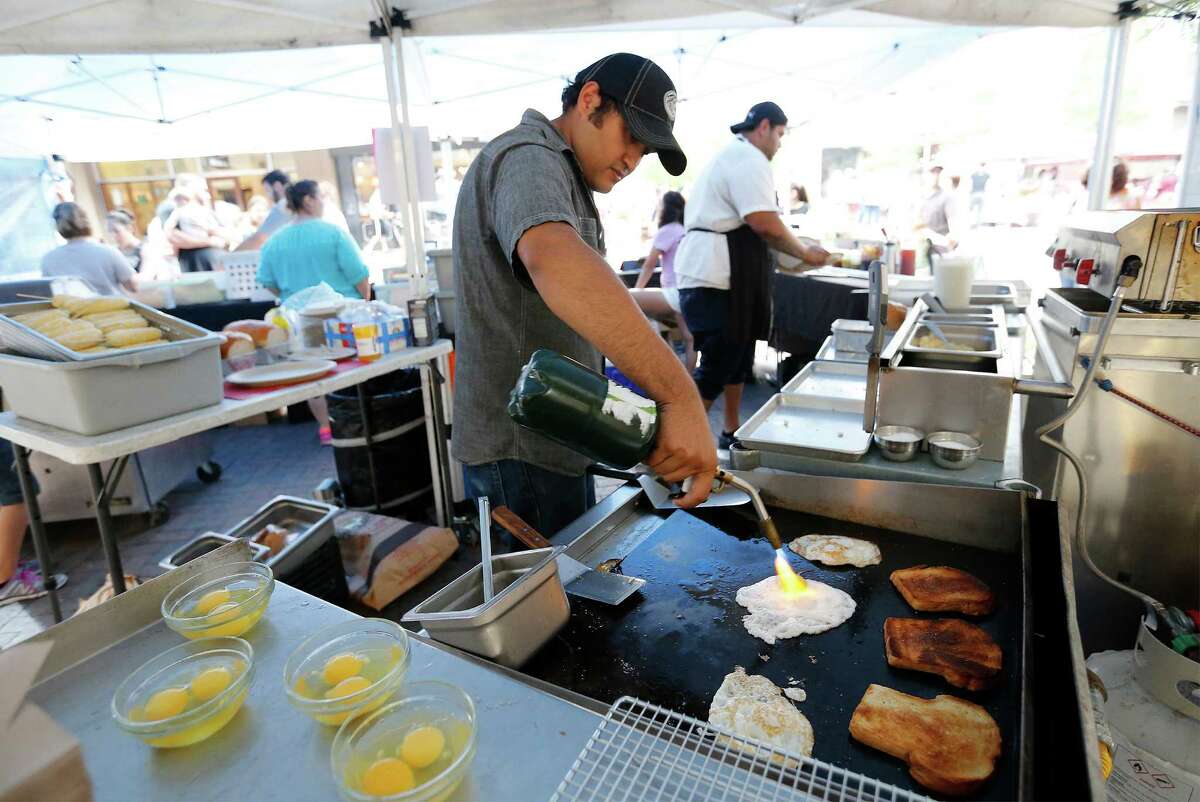 Humble House proprietor Luis Morales (center) uses a hand-held torch to aid the cooking of an egg as vendors using an open-flame grill and/or electric appliances for cooking food at The Pearl's farmers market are visited by a San Antonio Fire Department inspector on Saturday, May 21, 2016. A new fire inspection fee that was part of an ordinance approved in October went into effect for vendors. (Kin Man Hui/San Antonio Express-News)