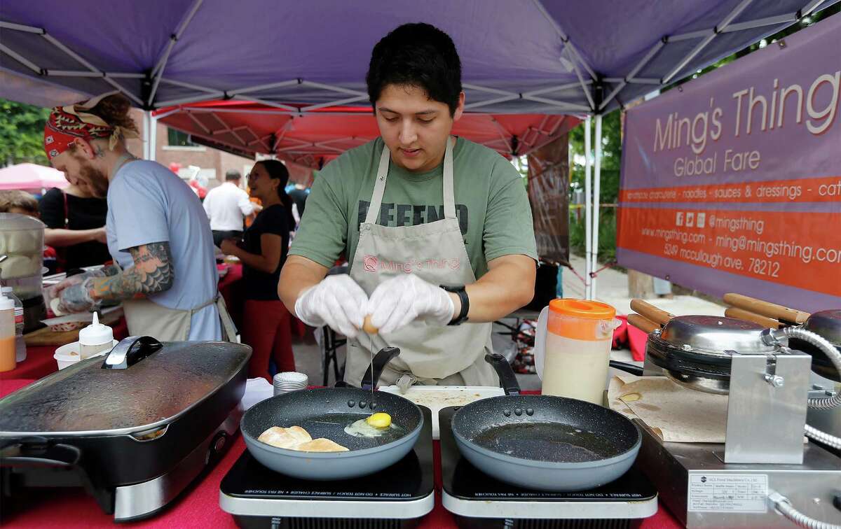 Ming's Thing manager Carlos Arredondo (center) cooks an egg as vendors using an open-flame grill and/or electric appliances for cooking food at The Pearl's farmers market are visited by a San Antonio Fire Department inspector on Saturday. A new fire inspection fee that was part of an ordinance approved in October went into effect for vendors.