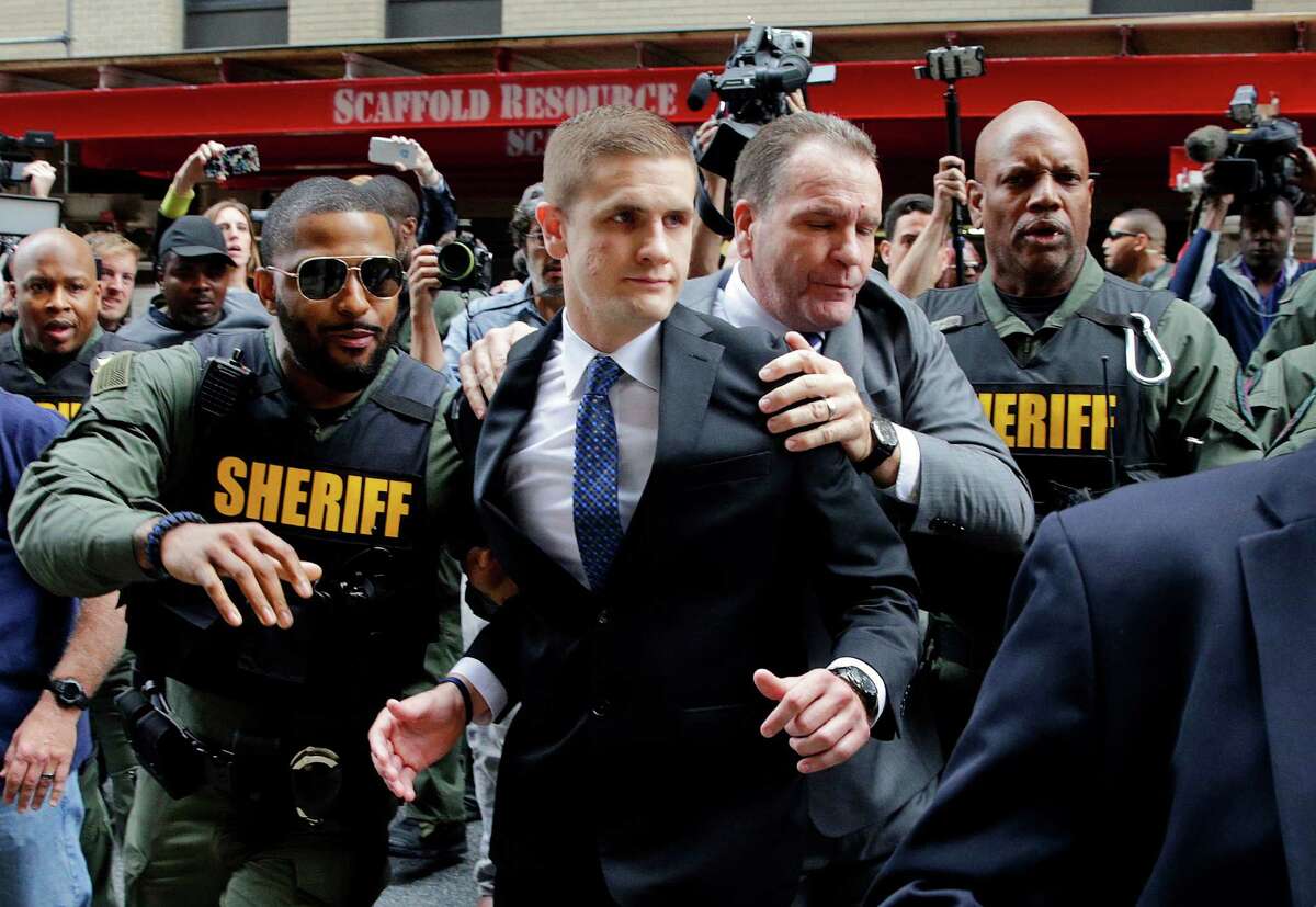 John Nero, center left, and Edward Nero, center right, brother and father of Officer Edward Nero, one of six Baltimore city police officers charged in connection to the death of Freddie Gray, are escorted out of a courthouse after Nero was acquitted of all charges in his trial in Baltimore, Monday, May 23, 2016. (AP Photo/Patrick Semansky)