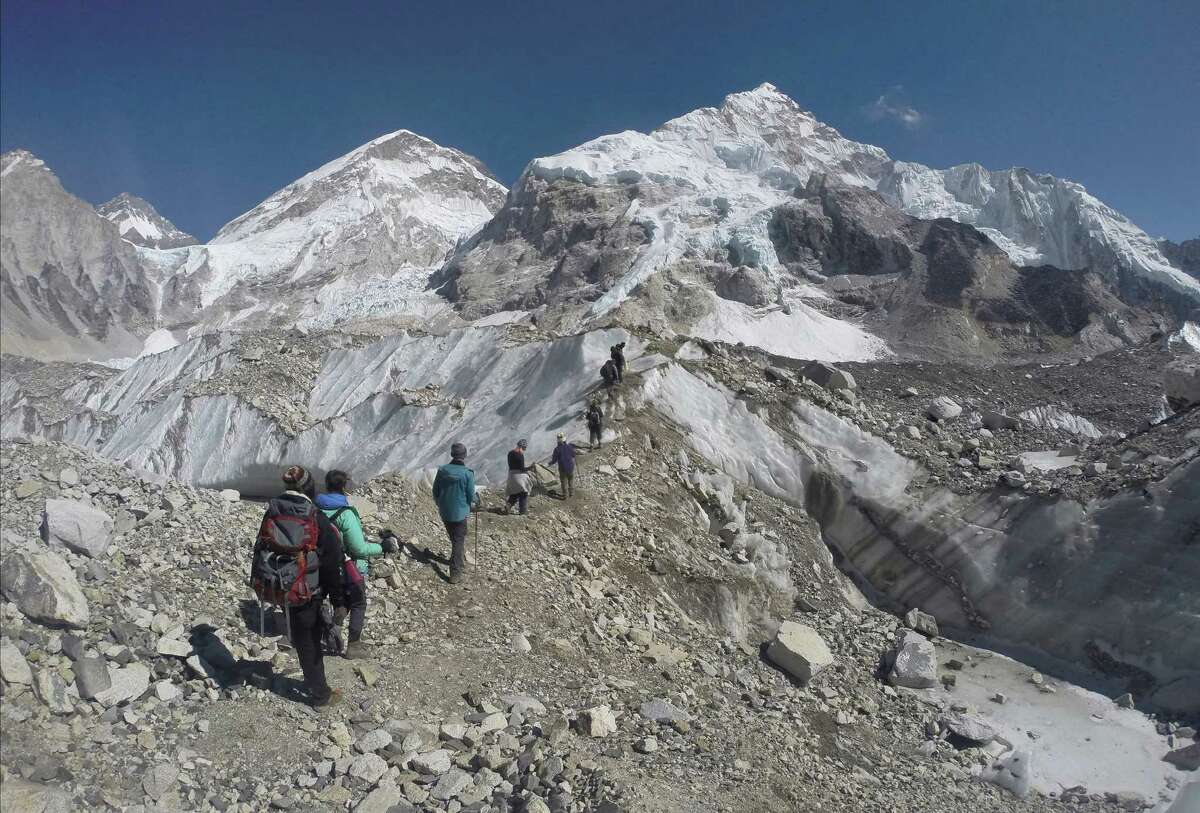FILE - In this Monday, Feb. 22, 2016 file photo, international trekkers pass through a glacier at the Mount Everest base camp, Nepal. An Indian climber has died while being helped down Mount Everest, just hours after a Dutch and an Australian climber died near the peak. Poor planning and overcrowding on the world's tallest peak may have led to bottlenecks that kept people delayed at the highest reaches while waiting for the path to clear lower down, Ang Tshering of the Nepal Mountaineering Association said Monday, May 23. (AP Photo/Tashi Sherpa, File)