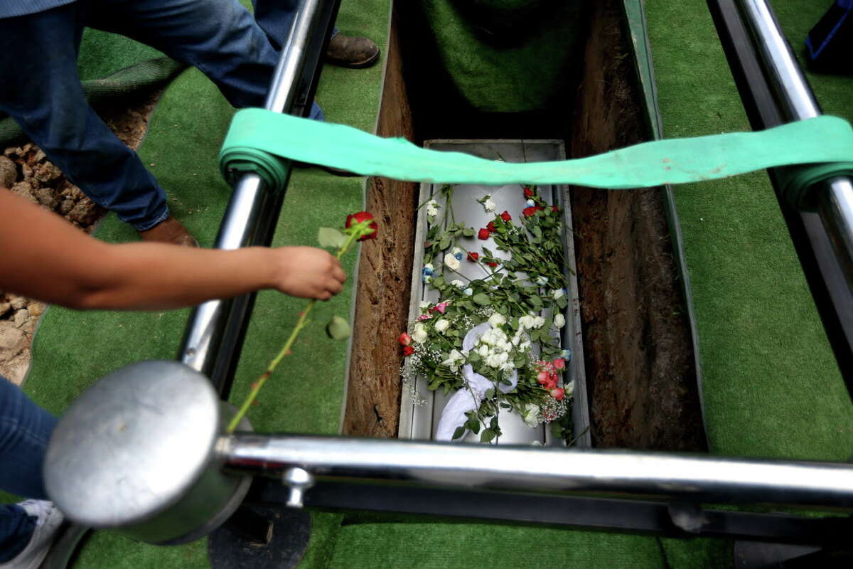 Flowers are tossed into the grave Josue Flores, 11-years-old, at the conclusion of a funeral service at Historic Hollywood Cemetery, Tuesday, May 24, 2016, in Houston. Josue was stabbed to death in north Houston as he walked home from school.
