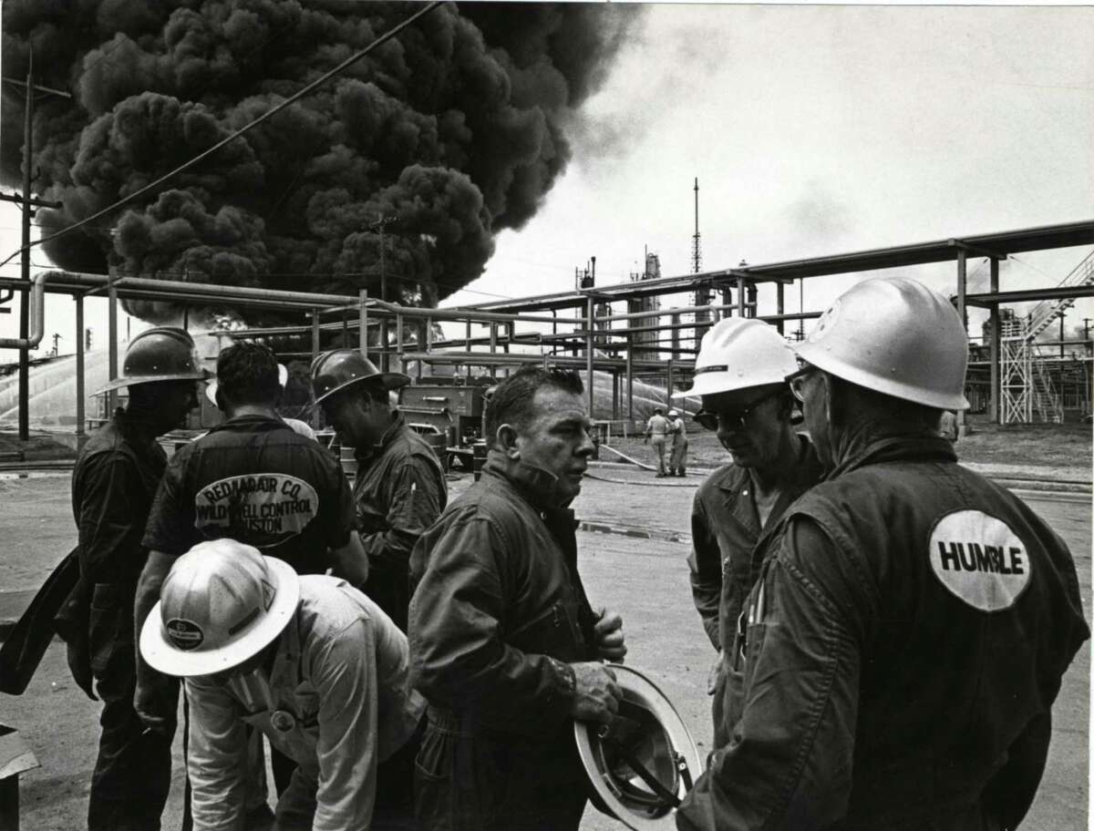 Red Adair, center, talks with workers from his "Red Adair Wild Well Control" team at a 1965 fire in Baytown.