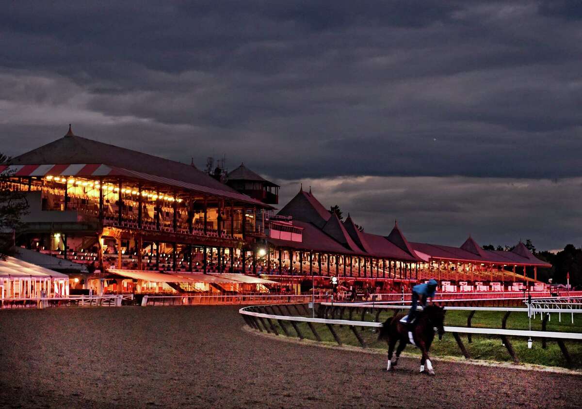A horse works in the early morning light Thursday morning, Aug. 27, 2015, at the Saratoga Race Course in Saratoga Springs, N.Y. The clubhouse is illuminated by the tote boards in the infield and the night lights in the structure. (Skip Dickstein/Times Union)