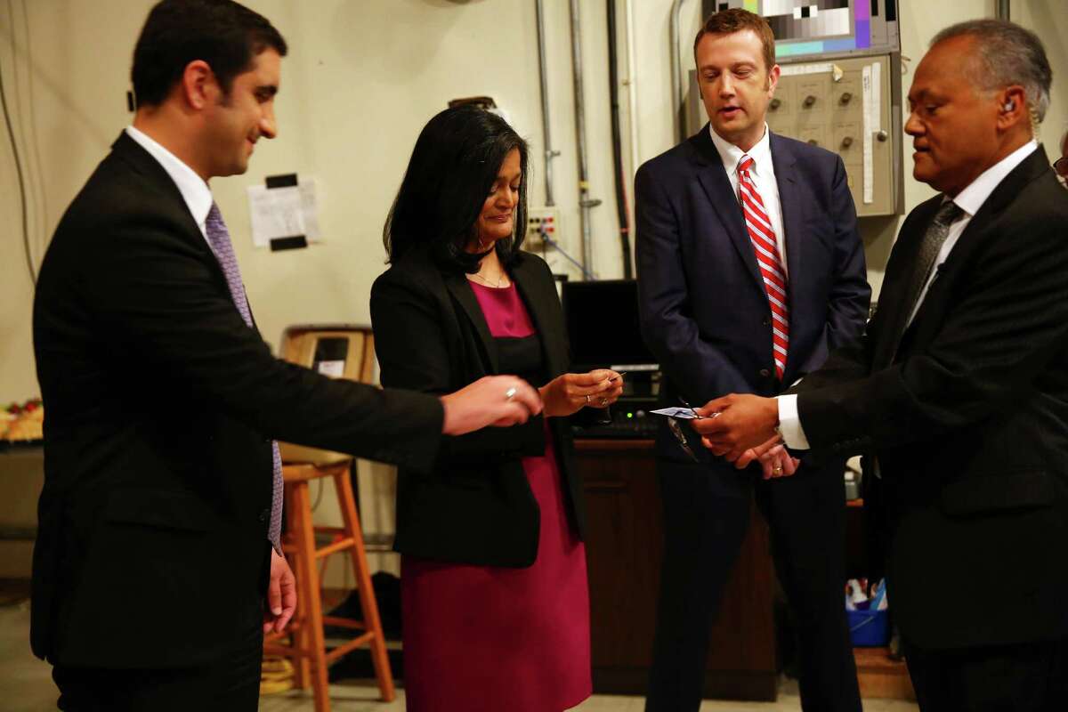 Moderator Enrique Cerna, right, hands out cards to candidates Brady Piniero Walkinshaw, left, Pramila Jayapal, and Joe McDermott to determine who will talk first in the 7th Congressional District democratic primary debate, Wednesday, May 25, 2016, the University of Washington.