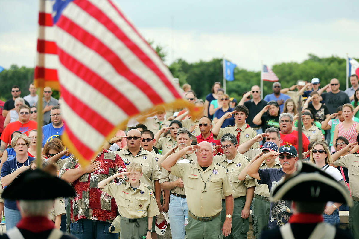 People salute during the Pledge of Allegiance Friday May 22, 2015 at Fort Sam Houston National Cemetery. About 1000 Boy Scouts, Girl Scouts and others placed American flags on graves to honor members of the military for Memorial Day.
