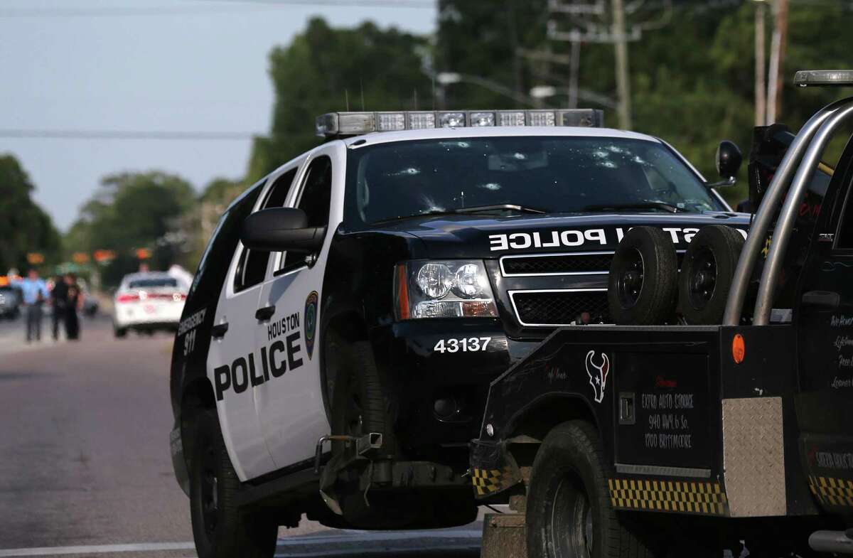 A Houston Police Department SUV that was hit with bullets 21 times is removed Sunday from an investigation scene on Memorial Drive near Wilcrest Drive. Two people, including a suspect, were killed in the shootout. Three other people and two constable's deputies were injured.