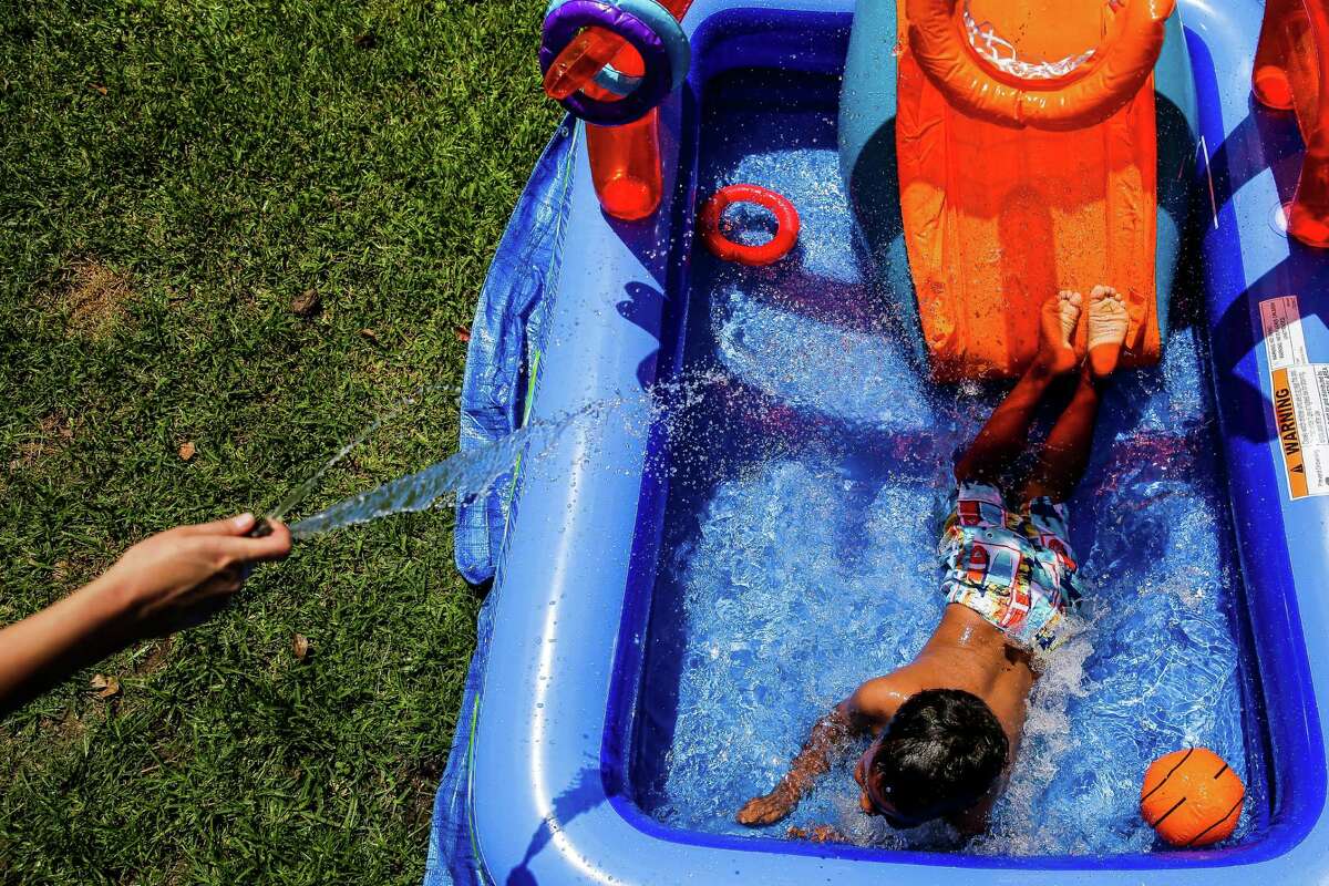 Carol Jeffery sprays her four-year-old foster child with the hose as they set up a new pool in their back yard Monday, May 23, 2016 in Houston. The foster parents, Jeffery and Angela Sugarek, welcomed their two foster kids, brothers ages 3 and 4, back into their home almost two months after Child Protective Services took the kids away after they reported the youngest child was being abused by an older brother.