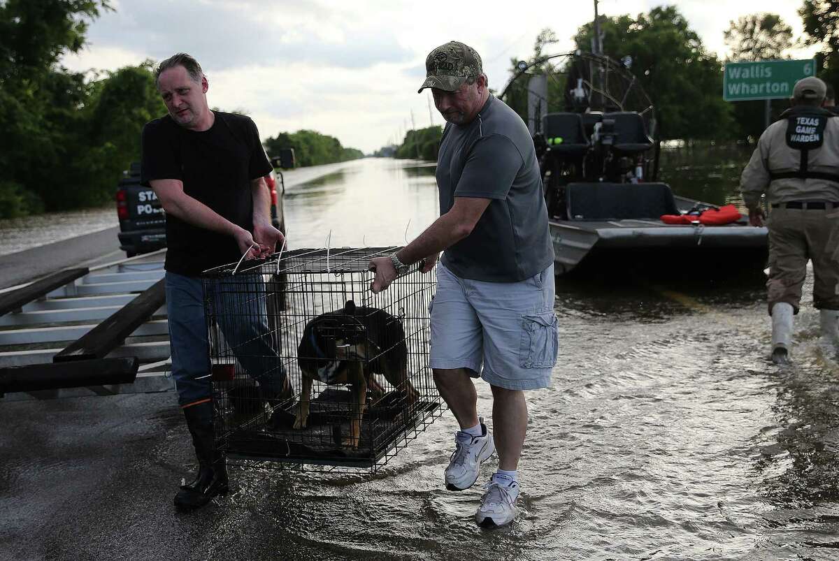 John Seger and his brother-in-law Roger Merrill carry Segar's dog after being rescued from his home as the Brazos River overflowed into his home on Monday, May 30, 2016, in Simonton.