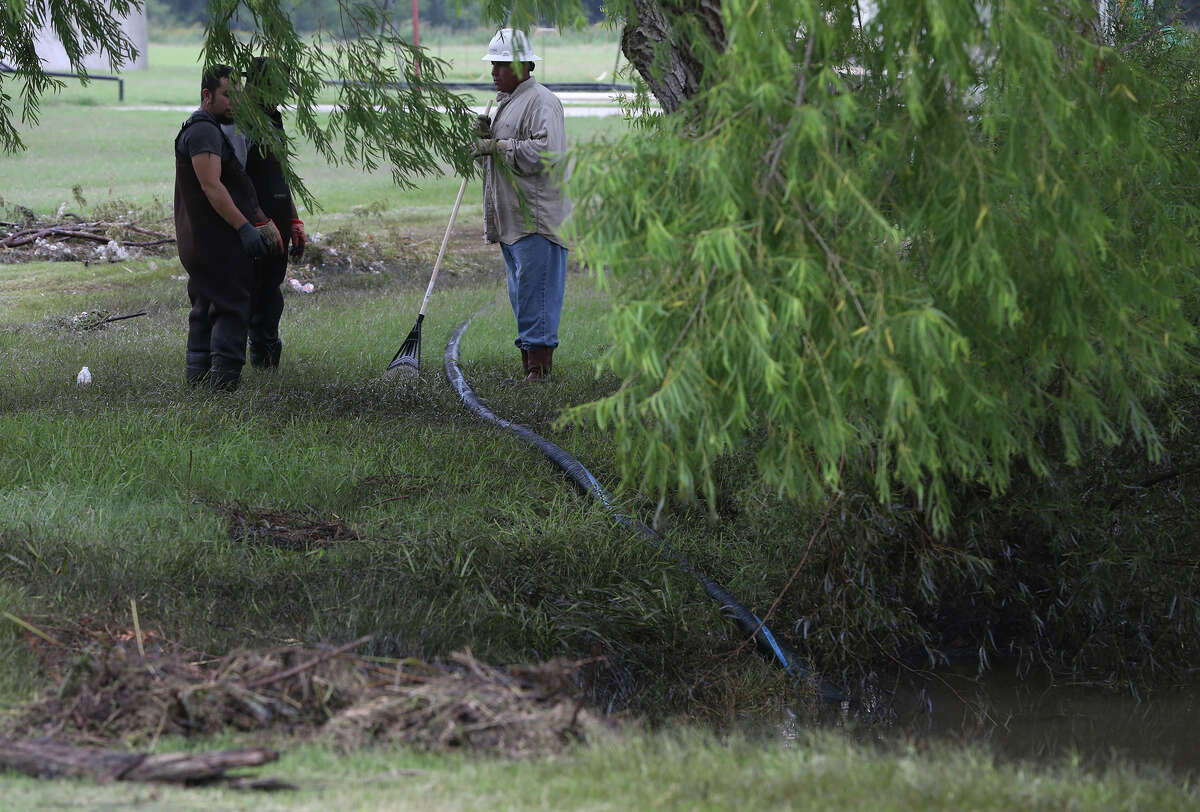 A crew with the FlowFect Company works Tuesday May 31, 2016 to to clean up an oil spill that took place near the Lakeshore Estates neighborhood in Lytle, Texas. Johnny Melancon, president of FlowFect, said lightning stuck an oil storage tank Sunday causing around 15 to 20 barrels of oil to leak and flow with rainwater into the neighborhood and a nearby pond. The crew is using a special soap to emulsify the oil.