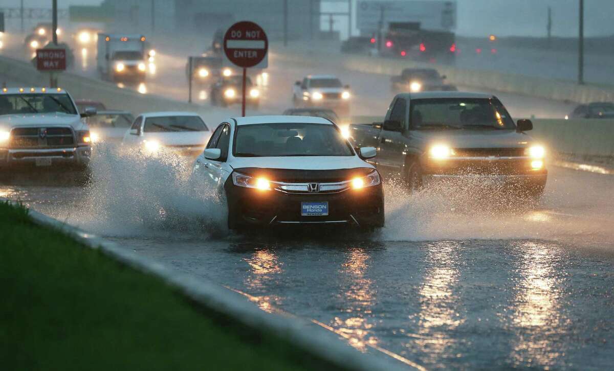 Cars splash through deep water accumulating fast on the access road to Loop 410 at Broadway during a heavy downpour in the area on May 31, 2016.
