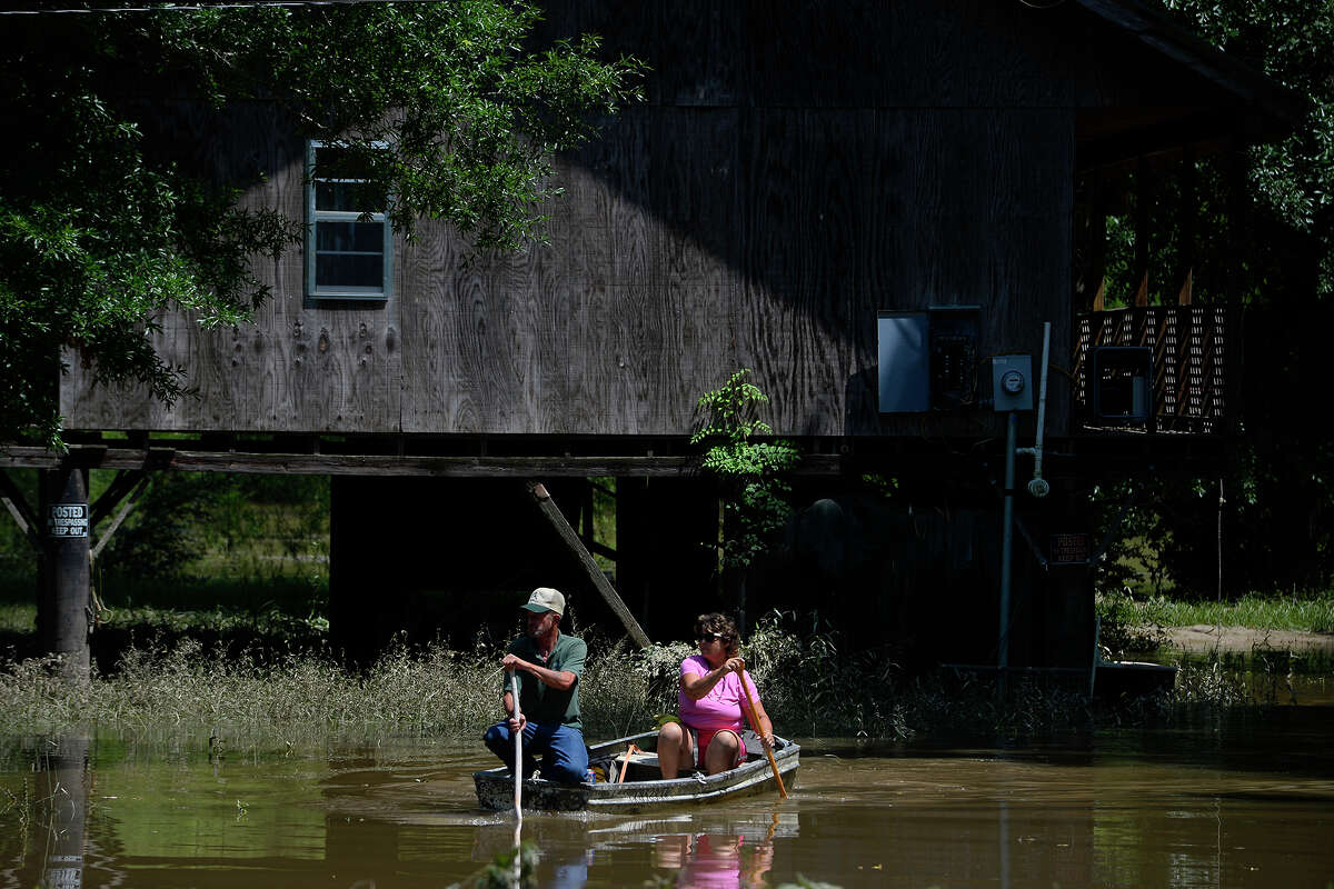 Lonnie and Connie Etie paddle a boat away from a house on the Neches River in Tyler County on Tuesday. The house, built on stilts, has stayed dry, but flood waters have surrounded it. Photo taken Tuesday 5/31/16 Ryan Pelham/The Enterprise