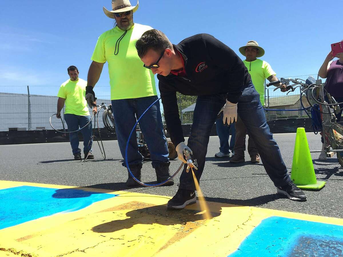 NASCAR driver AJ Allmendinger paints the curbing at Sonoma Raceway during a media event Wednesday.