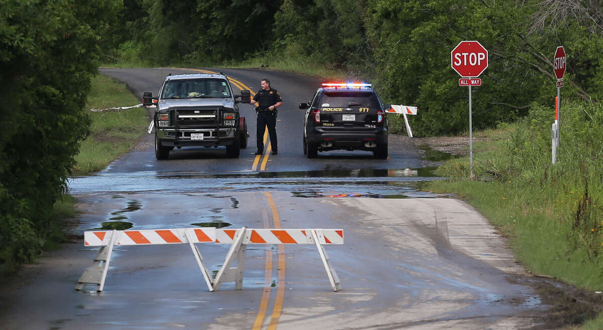 A San Antonio police officer stops motorists Thursday June 2 at Old O'Connor and Lookout roads where water is sweeping over the road after heavy rain fell in the area overnight.