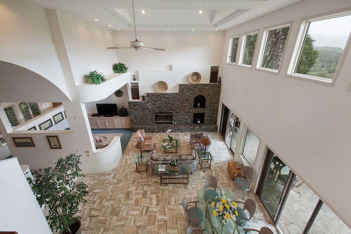 The living room features parquet flooring, a double height ceiling, patio access, and a fireplace with stone facade.