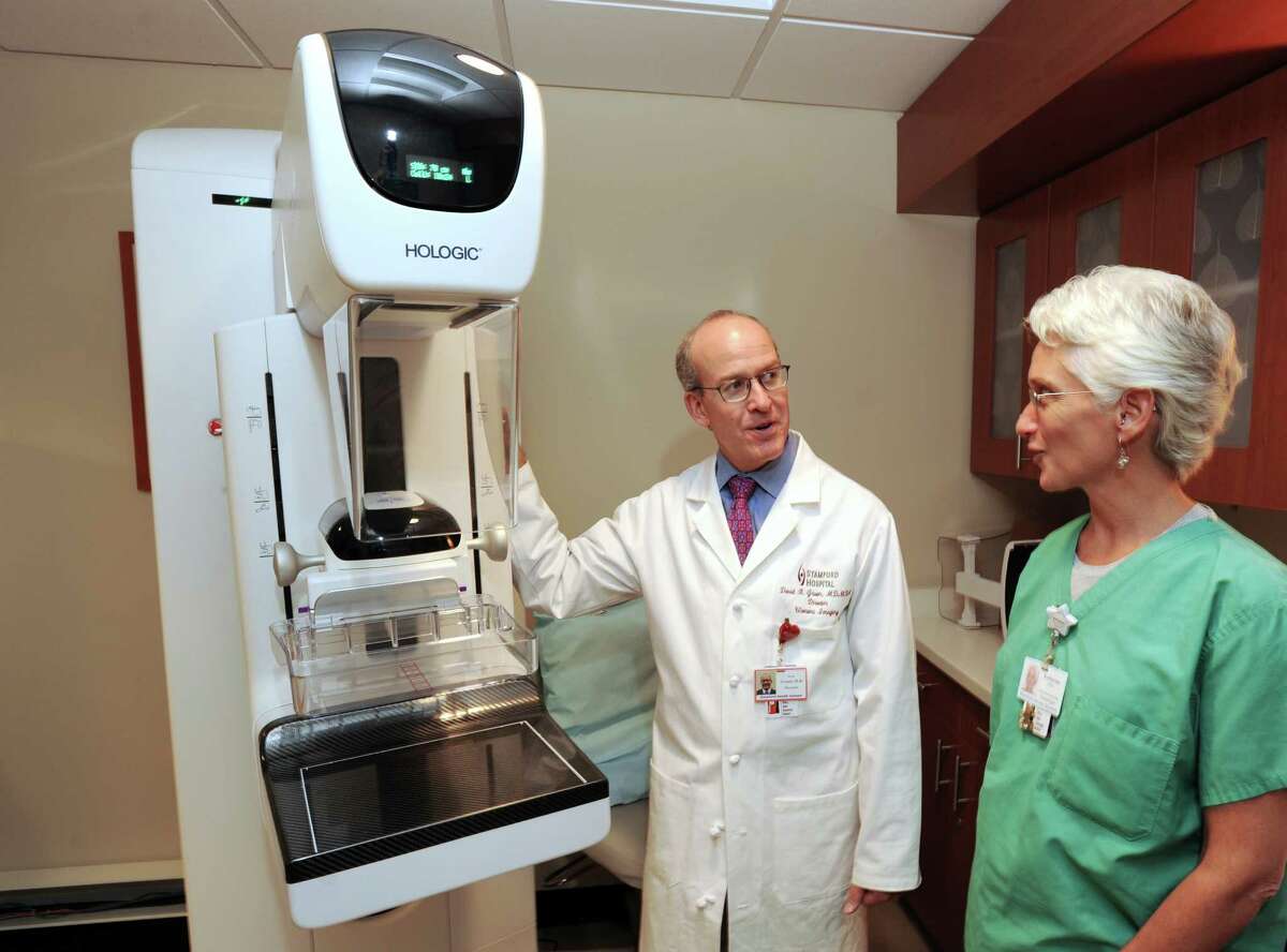 At left, Dr. David Gruen, Stamford Hospital director of women's imaging and co-director of breast cancer, speaks with Katharine Hollister, chief mammography technologist, about the Hologic breast tomosynthesis X-ray imaging system, background left, at the Tully Health Center, Stamford.