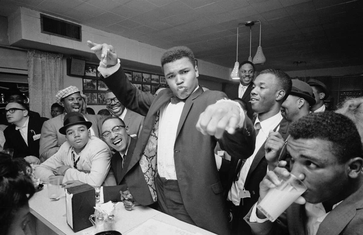 American boxer Classius Clay (later Muhammad Ali) (center), dressed in a tuxedo, holds court at a diner with fans, friends, and admirers after his defeat of Sonny Liston, Miami, Florida, March 1, 1964. Photo by Bob Gomel/The LIFE Images Collection/Getty Images)
