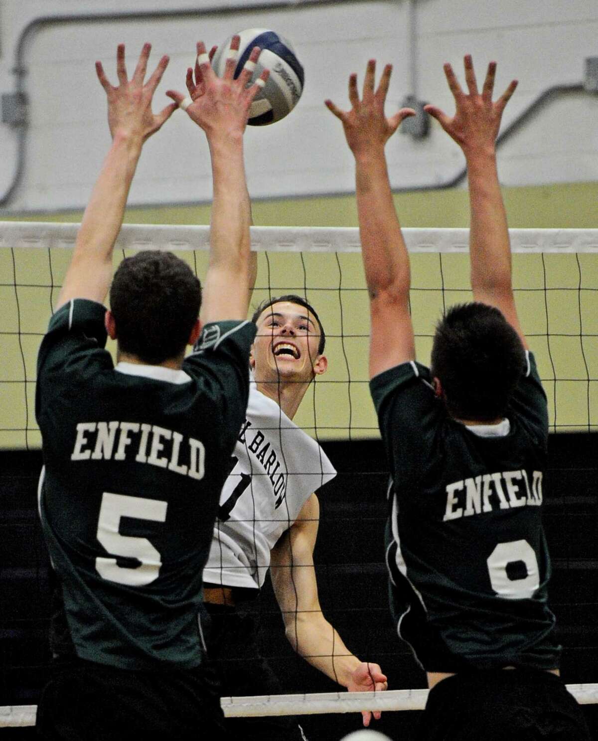 Joel Barlow's Ryan Corr (11) spikes the ball over Enfield's Dillon DeSouza (5) and Zachary Hirsch (8) in the State Class M boys volleyball quarterfinal game between Enfield and Joel Barlow high schools, on Friday night, June 3, 2016, at Joel Barlow High School, Redding, Conn.