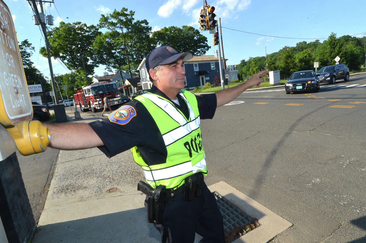 Westport Police Detective Phil Restieri motions to drivers to make the right turn on red onto Bridge st over the Saugatuck River bridge during rush hour traffic on Tuesday May 31 in Westport Conn.