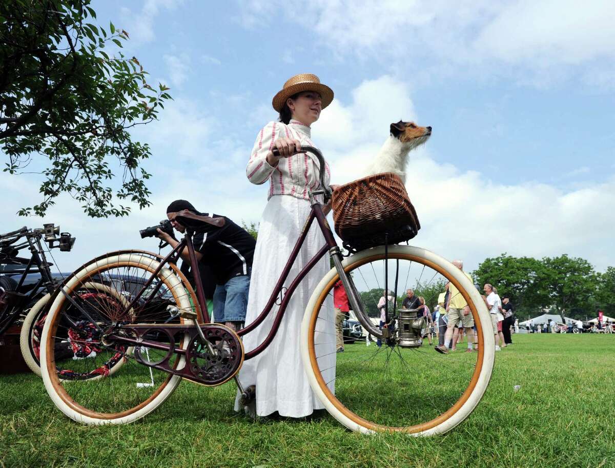 Dressed in a period costume, Dana Caton and her Jack Russell Terrier, Loki, with an 1899 Pierce Arrow bicycle during the Greenwich Concours d'Elegance at Roger Sherman Baldwin Park in Greenwich, Conn., Saturday, June 4, 2016. The show, considered by many to be one of the top ranked shows of its kind in the country, features vintage automobiles, vintage motorcycles, sports cars, electric cars, brand-new luxury models and various types of vehicles, is celebrating two decades of operation in Greenwich. Retired Brunswick School teacher Ted Stolar who said he loves cars and also said he has been coming to the show for ten years, called it a "religious experience." Sunday hours for the show are 10 a.m. to 5 p.m. One day tickets are $40 at the gate. Children under 12 are free with an adult. Parking for the show is located across the street from Roger Sherman Badlwin Park.
