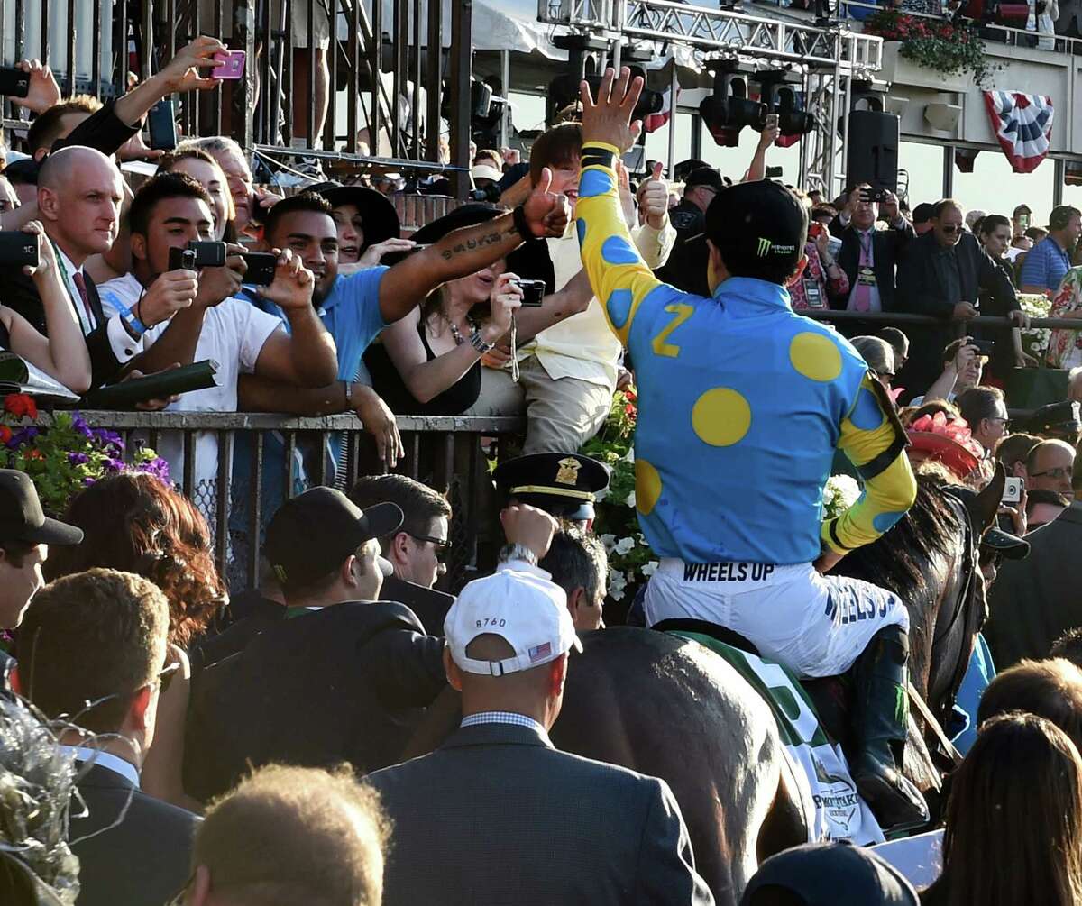 American Pharoah enters the winner's circle with jockey Victor Espinoza as a crowd of onlookers rejoice. Fans will not be allowed to take in the 2020 edition of the race. (Skip Dickstein/Times Union)