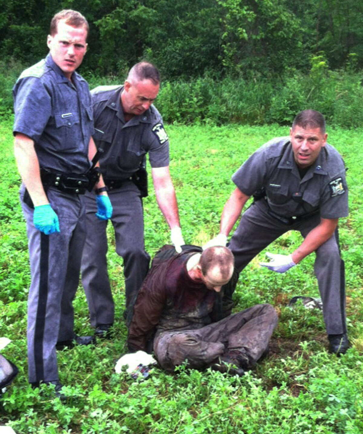 Police stand over David Sweat after he was shot and captured near the Canadian border Sunday, June 28, 2015, in Constable, N.Y. Sweat is the second of two convicted murderers who staged a brazen escape three weeks ago from a maximum-security prison in northern New York. His capture came two days after his escape partner, Richard Matt, was shot and killed by authorities. (AP Photo)