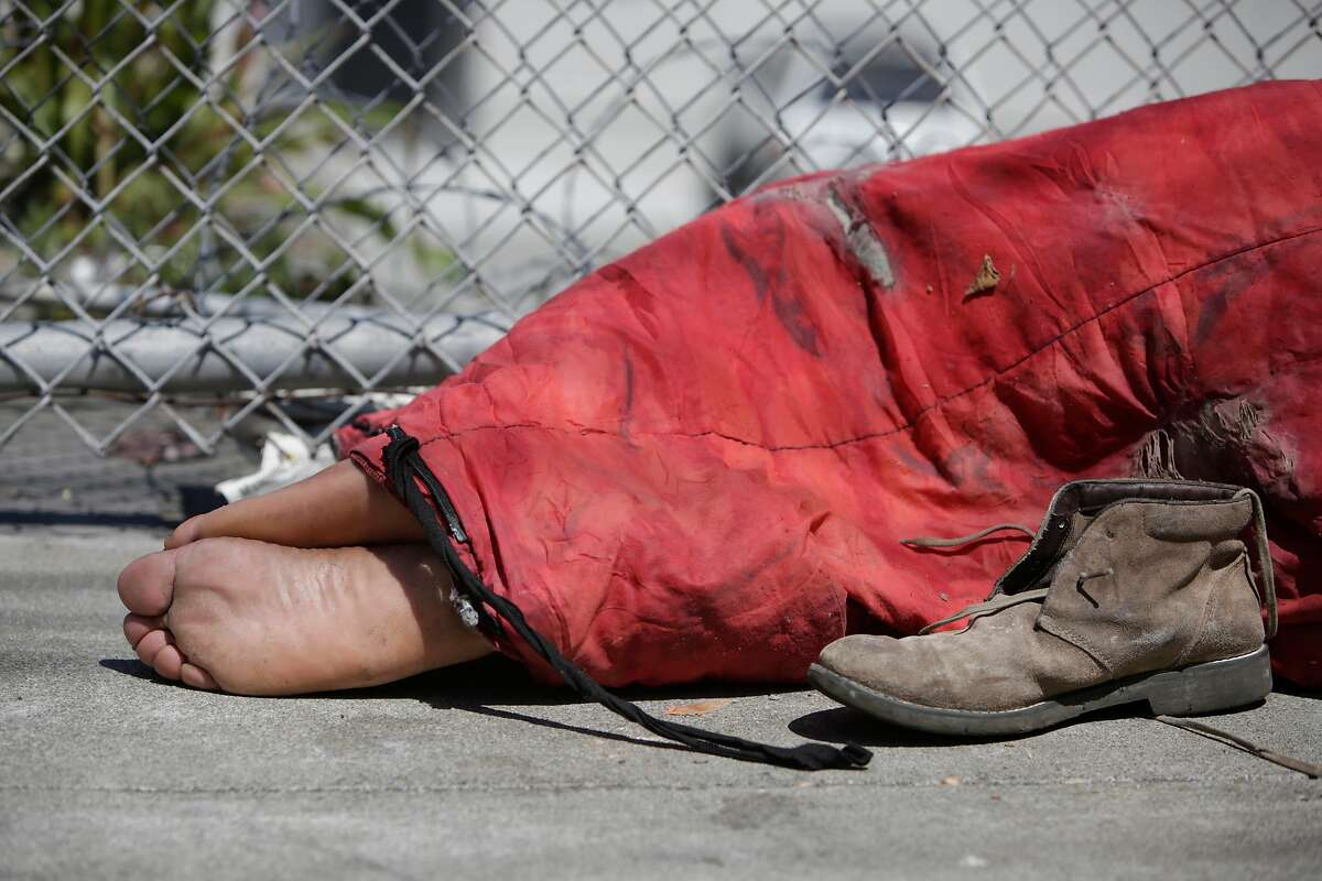 A man's feet stick out of a sleeping bag as he lays on Utah Street on Friday, May, 27, 2016 in San Francisco, California.