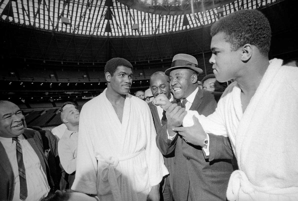 Muhammad Ali playfully throws a punch in the direction of Ernie Terrell as former heavyweight champion Sonny Liston, center, joins in the fun at a prefight medical exam in Houston on Feb. 1, 1967. ﻿