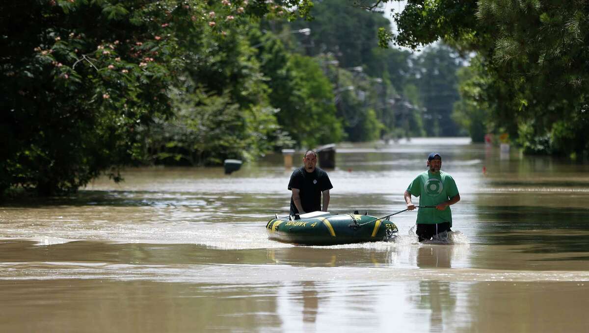 Thomas Wirtjes, left, and Tad Gibson, right, use a rubber boat on Hamblen Road, to bring back supplies to their homes surrounded by flood waters in the Forest Cove neighborhood, south of Kingwood, where flood waters from the San Jacinto Rivers reached levels not seen since 1994, Sunday, May 29, 2016, in Humble. ( Karen Warren / Houston Chronicle )