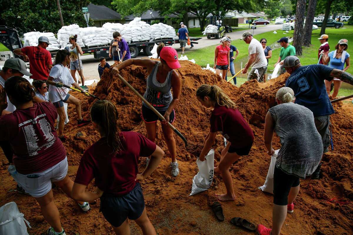 April Kondra, center left, and her daughter, Kate Kondra, 11, help fill sand bags ﻿in West Columbia. Community members have rallied together to build thousands of feet of dams to protect the city from flooding. ﻿