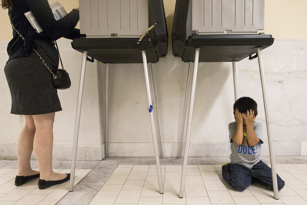 Johnny Lucero, 3, plays underneath a polling box while his mother, Nicanora Contreras, casts her vote during California's primary election day at City Hall in San Francisco, Tuesday, June 7, 2016. (Jessica Christian/The San Francisco Examiner via AP) MANDATORY CREDIT