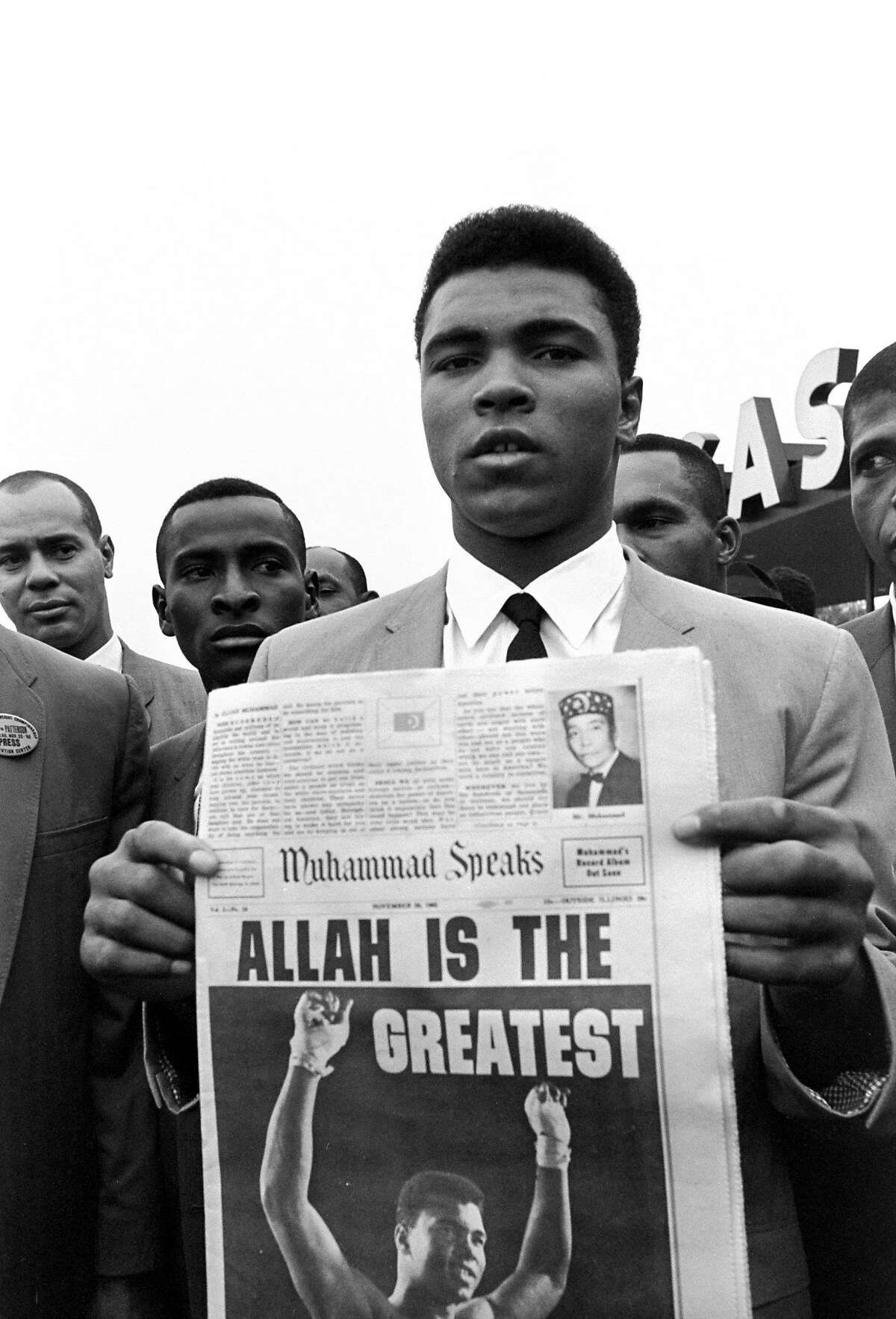 FILE - In this Nov. 22, 1965 file photo, heavyweight champion Muhammad Ali, holds a "Muhammad Speaks" newspaper bearing his picture as he and followers of the Muslim sect leave the Las Vegas convention center after weigh-in ceremonies to defend his title against challenger Floyd Patterson. In a 1964 interview with The Associated Press in which he formally declared himself a Muslim, Ali said he didn�t like the phrase �Black Muslims,� and described Islam as �the true way to save the world, which is on fire with hate.� He declared "forced and token integration" was a "pacifier," or temporary solution to problems blacks face, and one group should not impose its culture on another. (AP Photo/Sal Veder)
