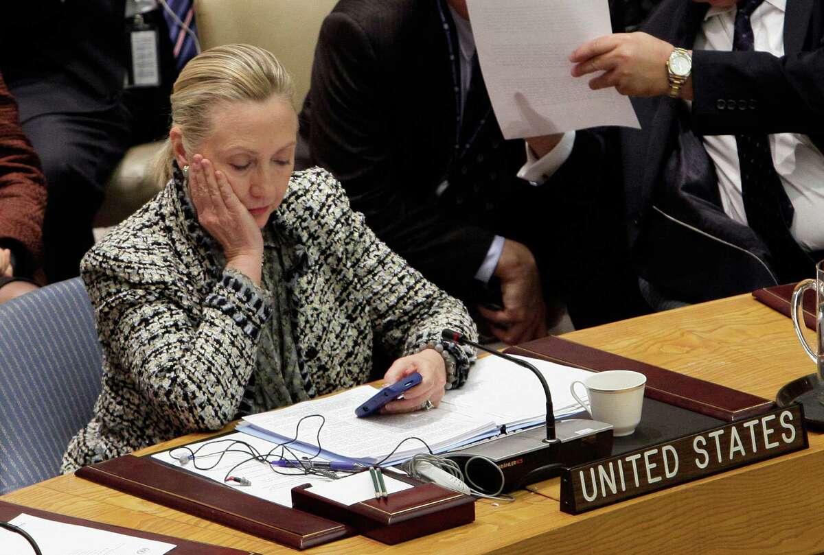 FILE - In this March 12, 2012 file photo, then-Secretary of State Hillary Rodham Clinton checks her mobile phone after her address to the Security Council at United Nations headquarters. The names of CIA personnel could have been compromised not only by hackers who may have penetrated Hillary ClintonÂ?’s private computer server or the State Department system, but also by the release itself of tens of thousands of her emails. (AP Photo/Richard Drew, File)
