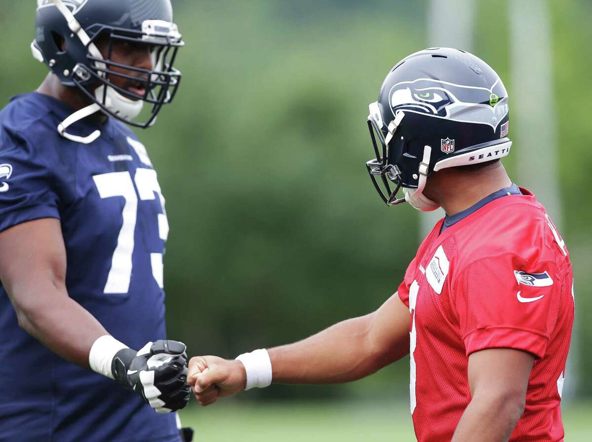 Quarterback Russell Wilson, right, greets tackle J'Marcus Webb during a Seahawks pre-season practice at the Virginia Mason Athletic Center, Thursday, June 9, 2016.