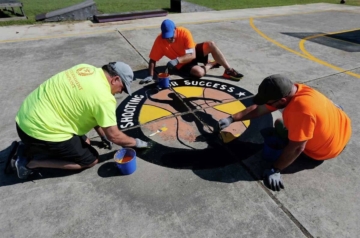 H-E-B employees Matt Serrano (from right), Mark Powers and corporate partner Stacy Wright of Tyson Foods help repaint a basketball court logo as employees and partners join together for the 31st annual H-E-B Tournament of Champions, a major community event which involves service projects across the city on Thursday, June 9, 2016. St. Jude's Ranch for Children was one of the beneficiaries of the event as numbers of volunteers all gathered to refresh the Hill Country campus between Bulverde and Spring Branch. Tasks included painting, landscaping and cleaning the facility which provides for abused, neglected and abandoned children. (Kin Man Hui/San Antonio Express-News)